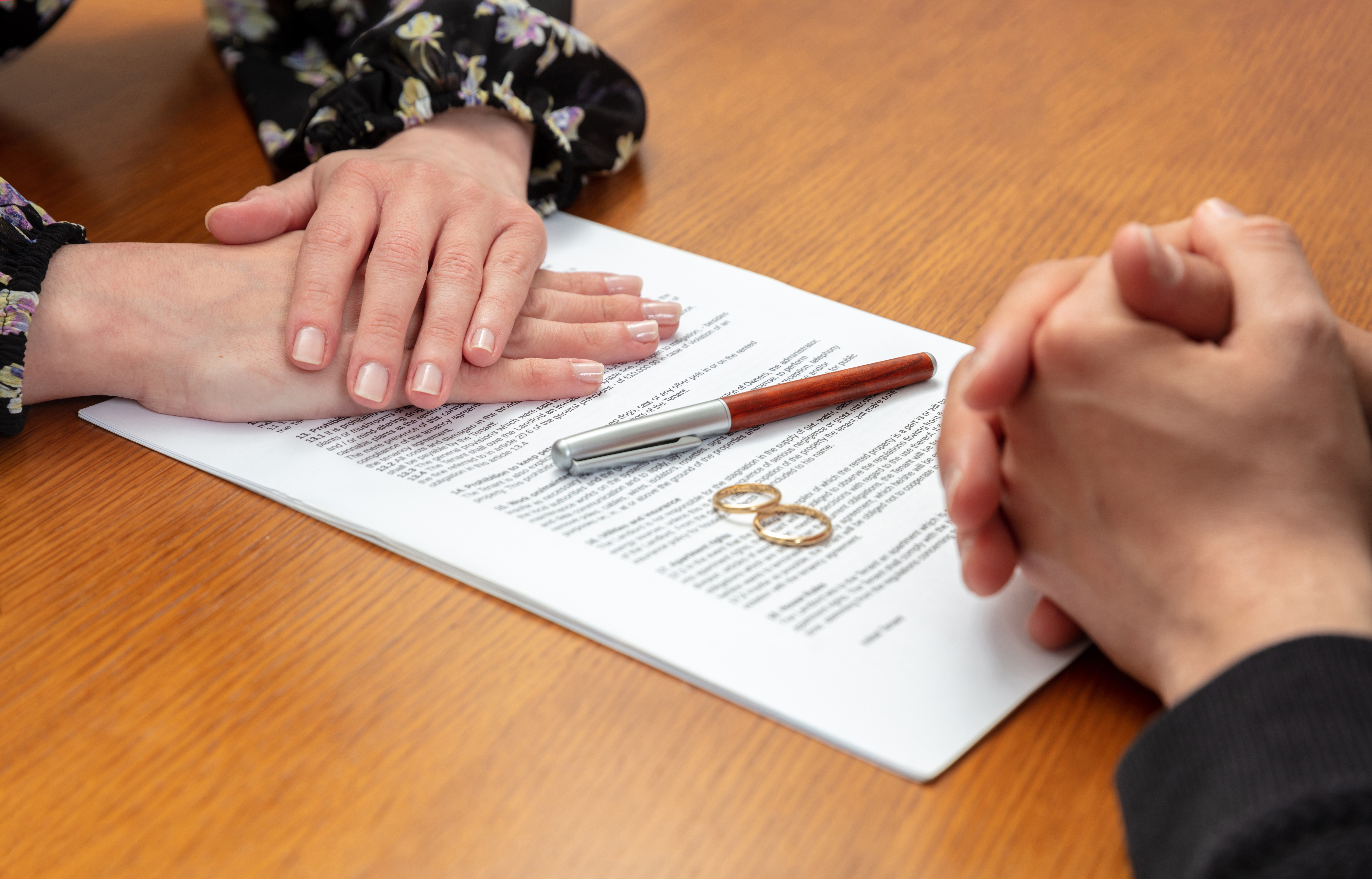 Divorce signature, marriage dissolution document. Wedding ring and agreement on lawyer office table